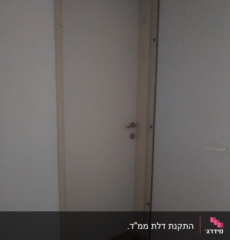 דלת לבנה עם ידית מתכת במסגרת עץ